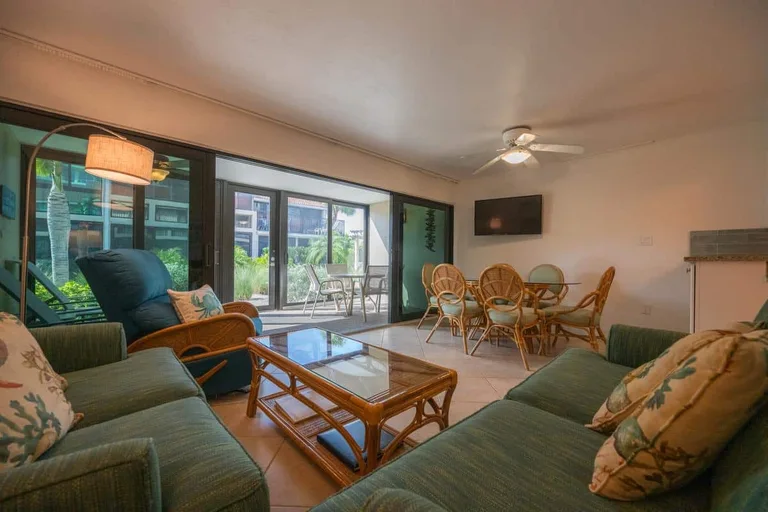B06 living and dining area with green seating, glass tables, and enclosed lanai for Casa Del Mar Unit B06 on Longboat Key