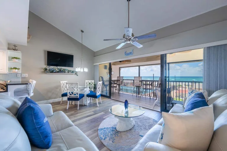 C15 living and dining area with white sofas, television and Gulf view through the lanai doors. for Casa Del Mar Unit C15 on Longboat Key