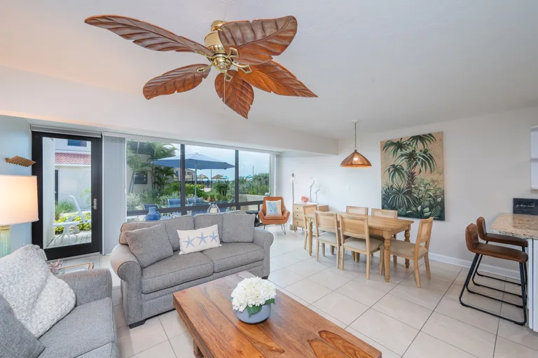 F01 living and dining area with sofas and glass doors to the courtyard patio. for Casa Del Mar Unit F01 on Longboat Key